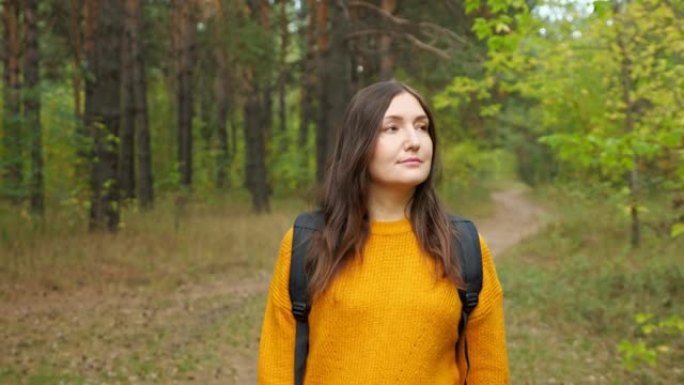 快乐的女徒步旅行者沿着绿色森林漫步