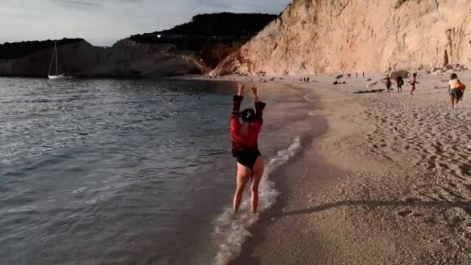 摄像机在日落时在海边的跳舞女孩周围旋转