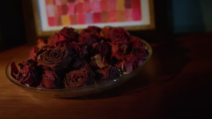 美丽的盘子，干燥的玫瑰花瓣站在桌子上。带干花的菜