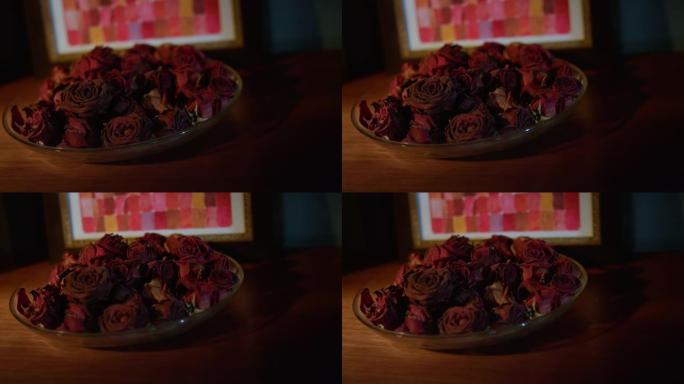 美丽的盘子，干燥的玫瑰花瓣站在桌子上。带干花的菜