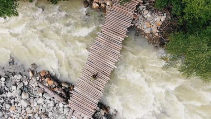 一个背着背包的女旅行者在一座木桥上走过暴风雨的山河鸟瞰图