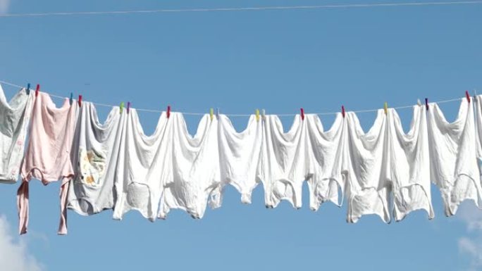 晾衣绳，在阳光明媚的夏日，面对蓝天，用干净的白色衣服绳子。绳子上晾干衣服，视频4k分辨率