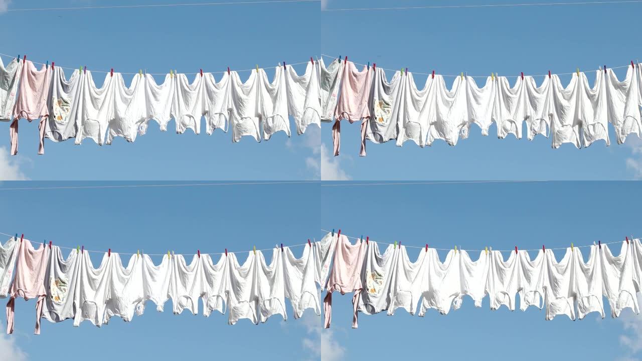 晾衣绳，在阳光明媚的夏日，面对蓝天，用干净的白色衣服绳子。绳子上晾干衣服，视频4k分辨率