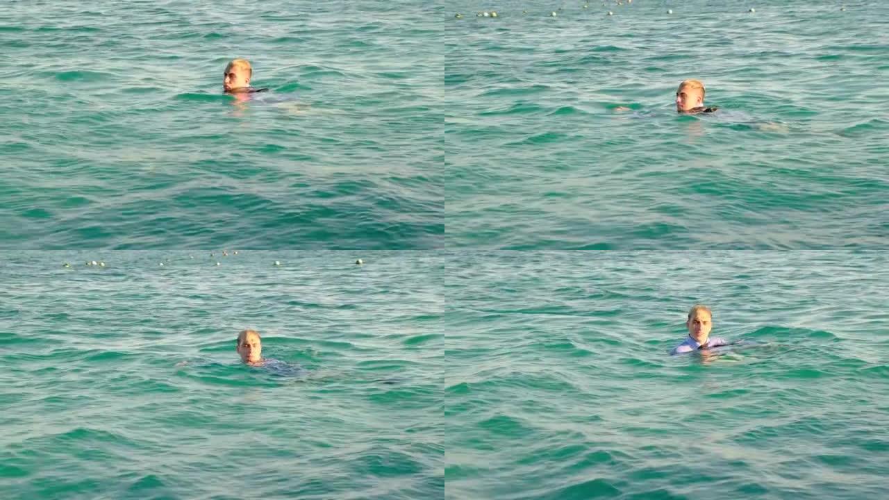 一个穿着衬衫和领带的有趣男人在阳光明媚的日子在海里游泳。4k
