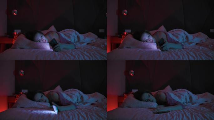 年轻女子难以入睡检查手机一个年轻女子晚上躺在床上