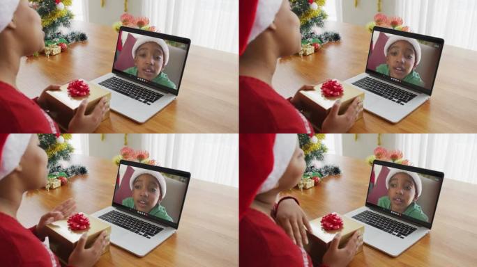 戴着圣诞老人帽子的非洲裔美国妇女使用笔记本电脑进行圣诞节视频通话，屏幕上有男孩