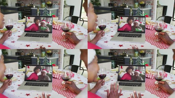 非裔美国人夫妇与葡萄酒使用笔记本电脑与家人在屏幕上进行圣诞节视频通话