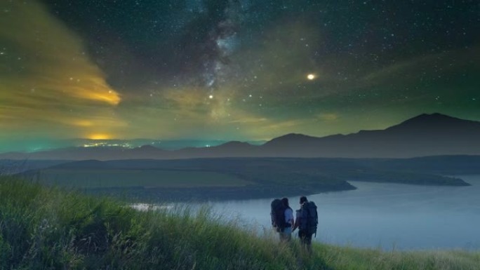 两位旅行者站在美丽的星空背景下的山顶上