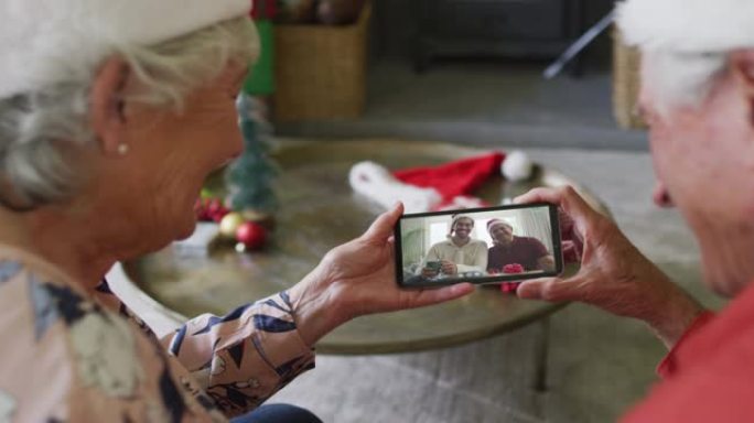 高级高加索夫妇使用智能手机进行圣诞节视频通话，屏幕上有微笑的家人