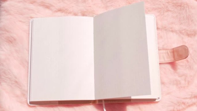 粉色人造毛皮平铺上的空白笔记本模型。珊瑚蓬松女性织物背景俯视图。女性博客玫瑰纺织品表面记事本复制空间
