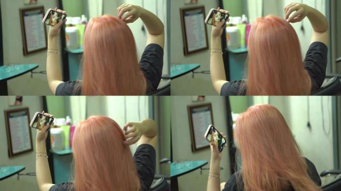 年轻女子在美容院垂死头发，使用智能手机进行自拍