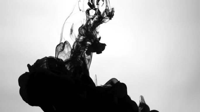 白色背景上的水中黑色水彩墨水。黑色墨滴在水中的慢动作。