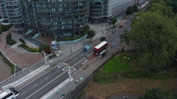 现代住宅区道路鸟瞰图。圆形公寓大楼。红色双层站在公共汽车站。英国伦敦