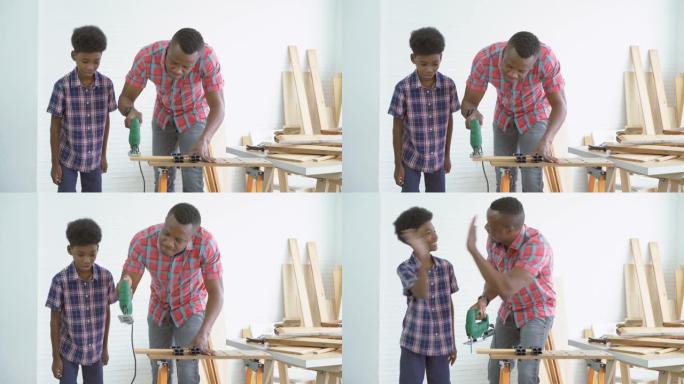 好奇的非洲裔美国儿童男孩在工厂里看着并学习父亲用电锯切割一块木头