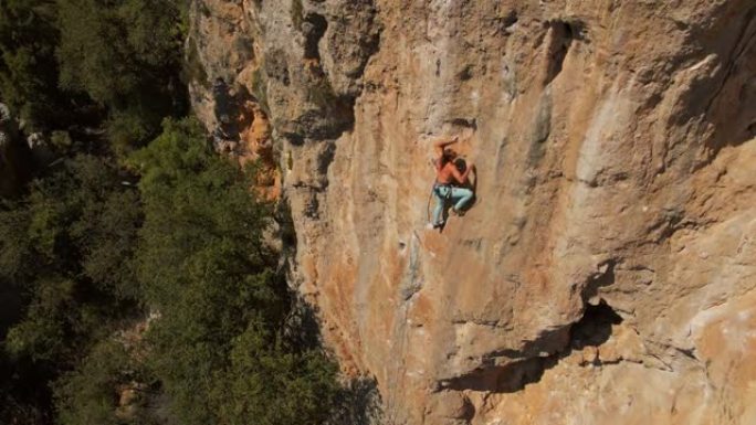 航拍镜头。强壮肌肉男无人机的视野在垂直石灰岩岩壁上攀登挑战性的攀岩路线