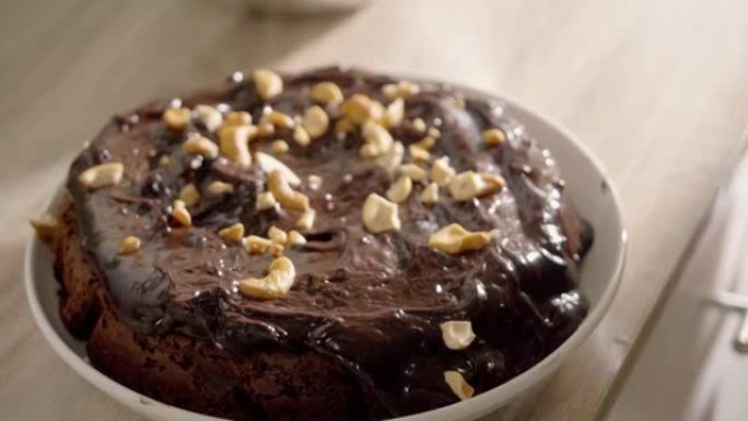 自制巧克力甘纳许蛋糕浇头，桌上有腰果，慢动作。