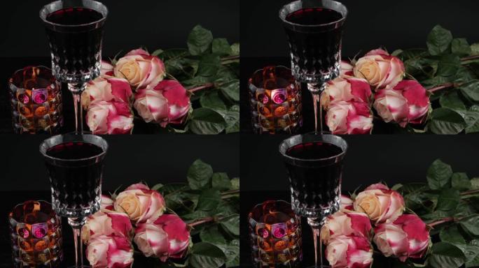 玫瑰花在水晶酒杯附近，红酒和燃烧的candele，黑色背景