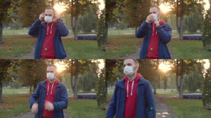 一名身穿红色连帽衫和蓝色风衣的年轻人在进入公共场所时脸上戴着保护性医用一次性口罩。秋季公园的反Cov