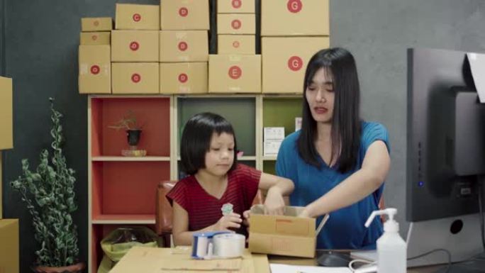 亚洲妇女和小女孩展示和包装箱集装箱在线销售在家里。