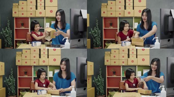 亚洲妇女和小女孩展示和包装箱集装箱在线销售在家里。
