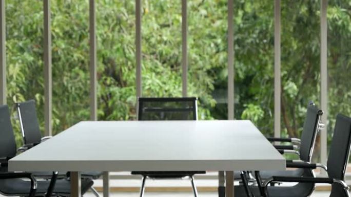 办公室会议室没有人空着，生态绿色自然。股东团队会议室办公室。白色木质桌子黑色椅子家具绿色背景。