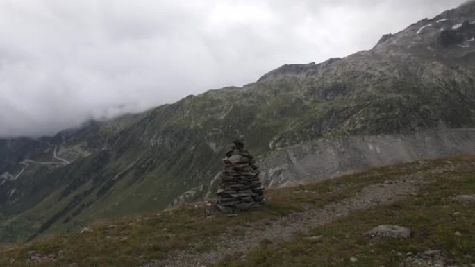 具有高山全景的山路上的石塔视图