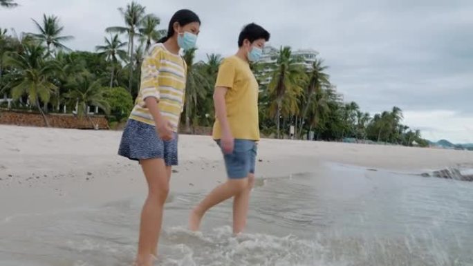 快乐的亚洲儿童一起在沙滩上踢水，生活方式理念。