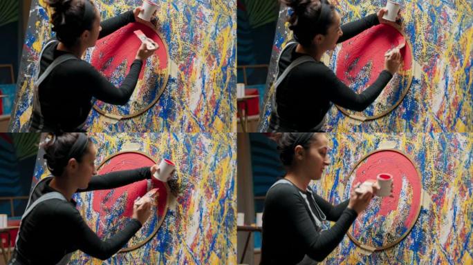 Fc二手画家站在画架附近，画布上正在创作最新的展览绘画。女人努力完成附于圆形模板的红色油漆中的杰作填