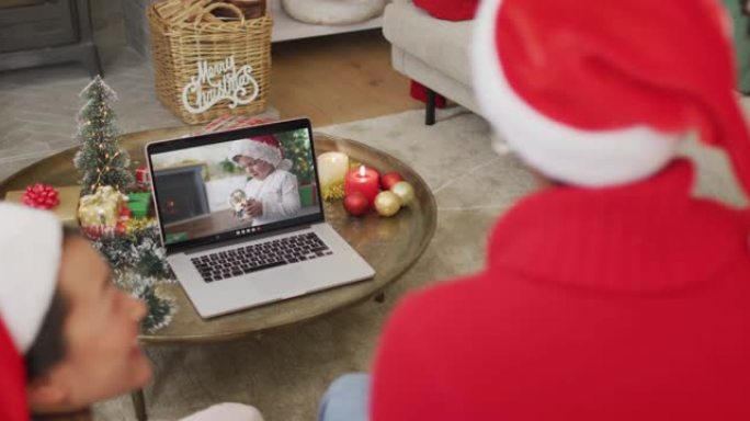 带圣诞老人帽子的非裔美国人家庭使用笔记本电脑进行圣诞节视频通话，屏幕上有男孩