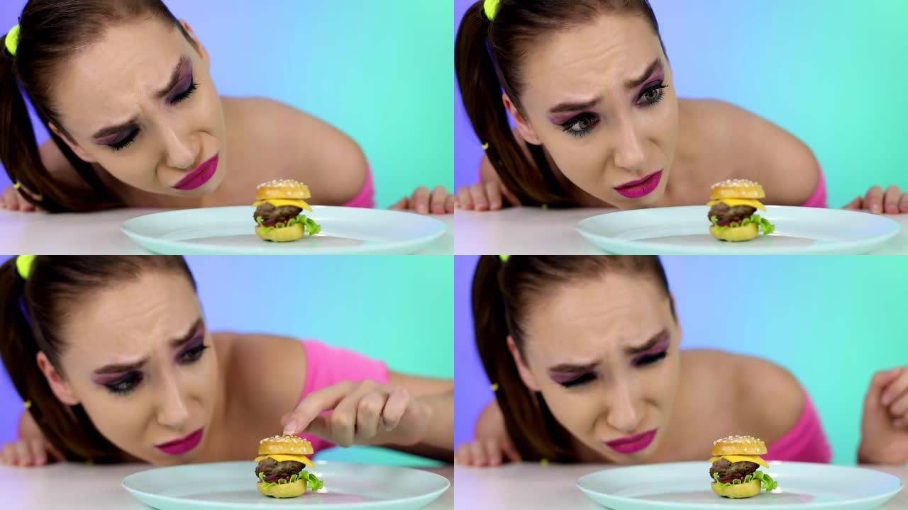 素颜的心烦意乱的女孩看着一个小汉堡。