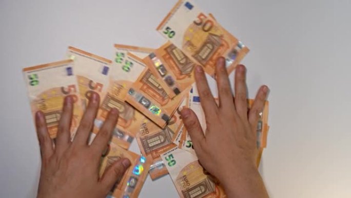 一名男子的手在白色背景上取下许多50欧元钞票的静态照片