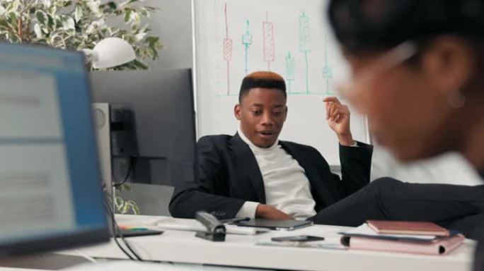 皮肤黝黑英俊的公司老板舒适地坐在椅子上，双脚躺在桌子上，闭着眼睛抬起头来迅速获得出色的想法登录计算机