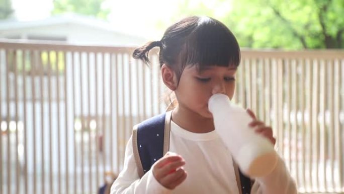 可爱的亚洲小女孩正在喝牛奶