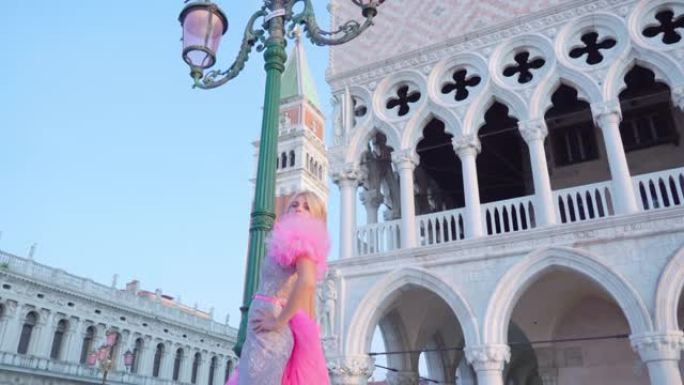 穿着粉红色连衣裙的女孩在圣马可塔前的威尼斯广场上移动