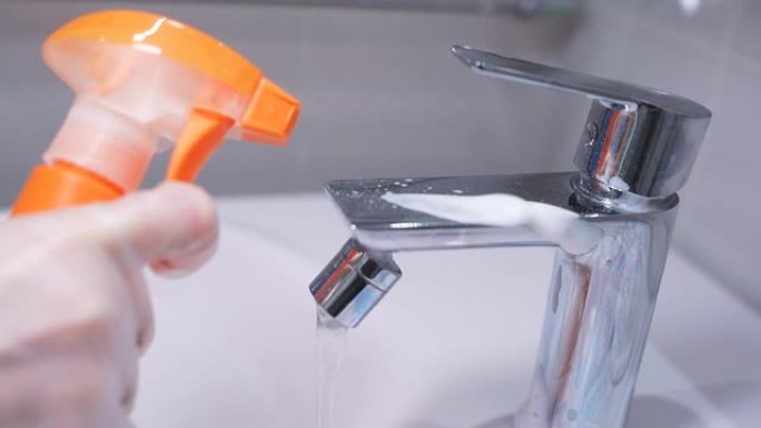 在浴室的镀铬水龙头上喷洒清洁剂的特写镜头。卫生，房屋清洁，从冠状病毒消毒。慢动作