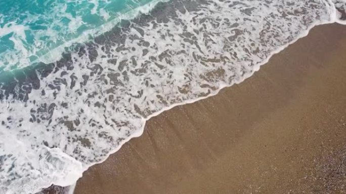 蓝浪冲向沙滩的俯视图。
