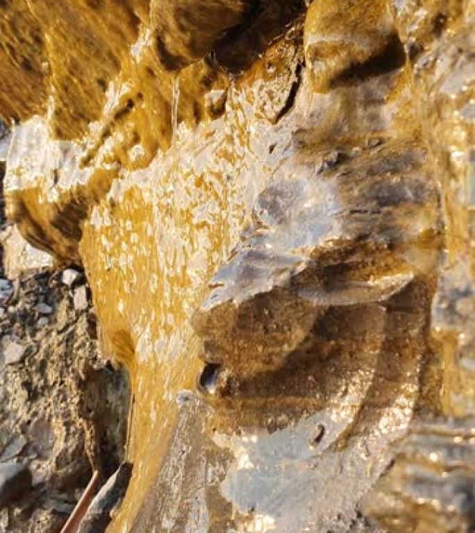 背景垂直视频，自然溪流顺着米色岩石滴落