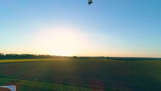 日落时机动悬挂式滑翔机在野外飞行