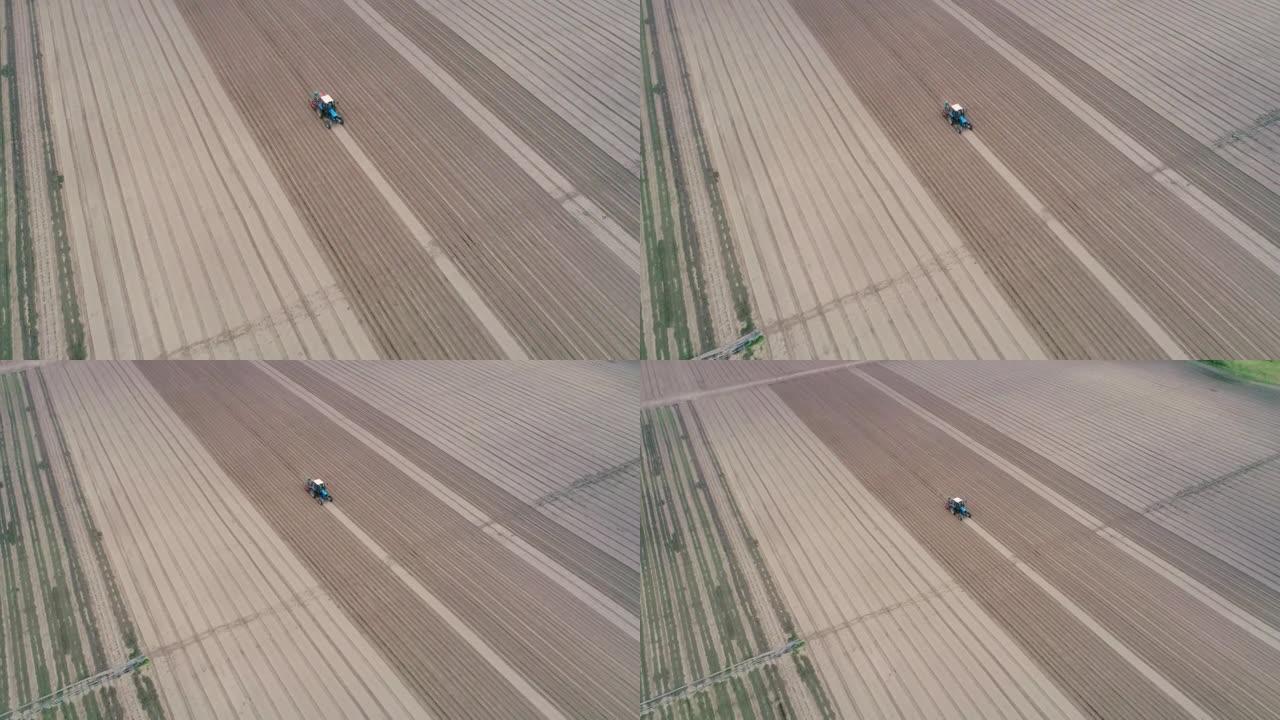 在现场安装灌溉系统。拖拉机在野外作业的航拍画面。种植胡萝卜