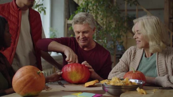 一位70岁的老人与家人坐在一张桌子旁，用种子清洗南瓜