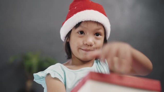 戴圣塔帽子的女孩打开礼品盒。
