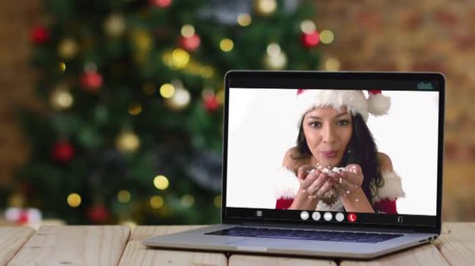 穿着圣诞老人服装的快乐白人妇女在笔记本电脑上进行视频通话，带有圣诞节装饰和树木