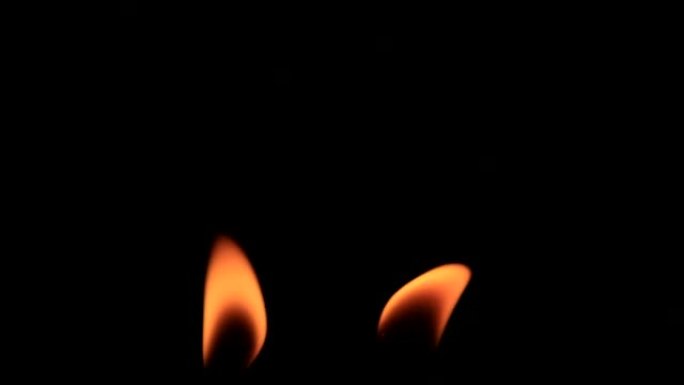 一对燃烧的蜡烛火焰在黑暗中移动的镜头