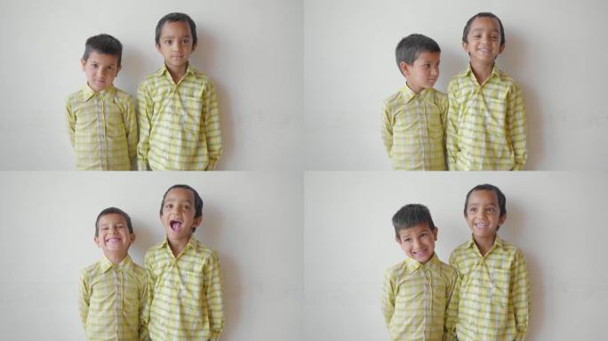 两个可爱的小小学生盯着站在白色墙壁上的相机。