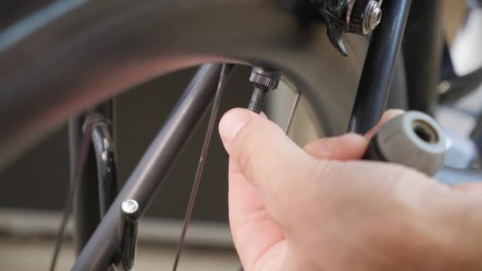 男性自行车技术员使用自行车泵将空气泵入轮胎后，从自行车轮胎上拧上盖子。自行车维修。修理自行车车间