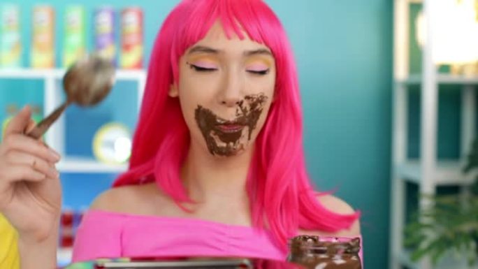 一个粉红色头发的女孩贪婪地用勺子吃巧克力