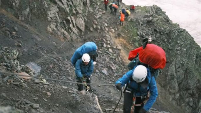 几个登山者抓住钢绳爬上山