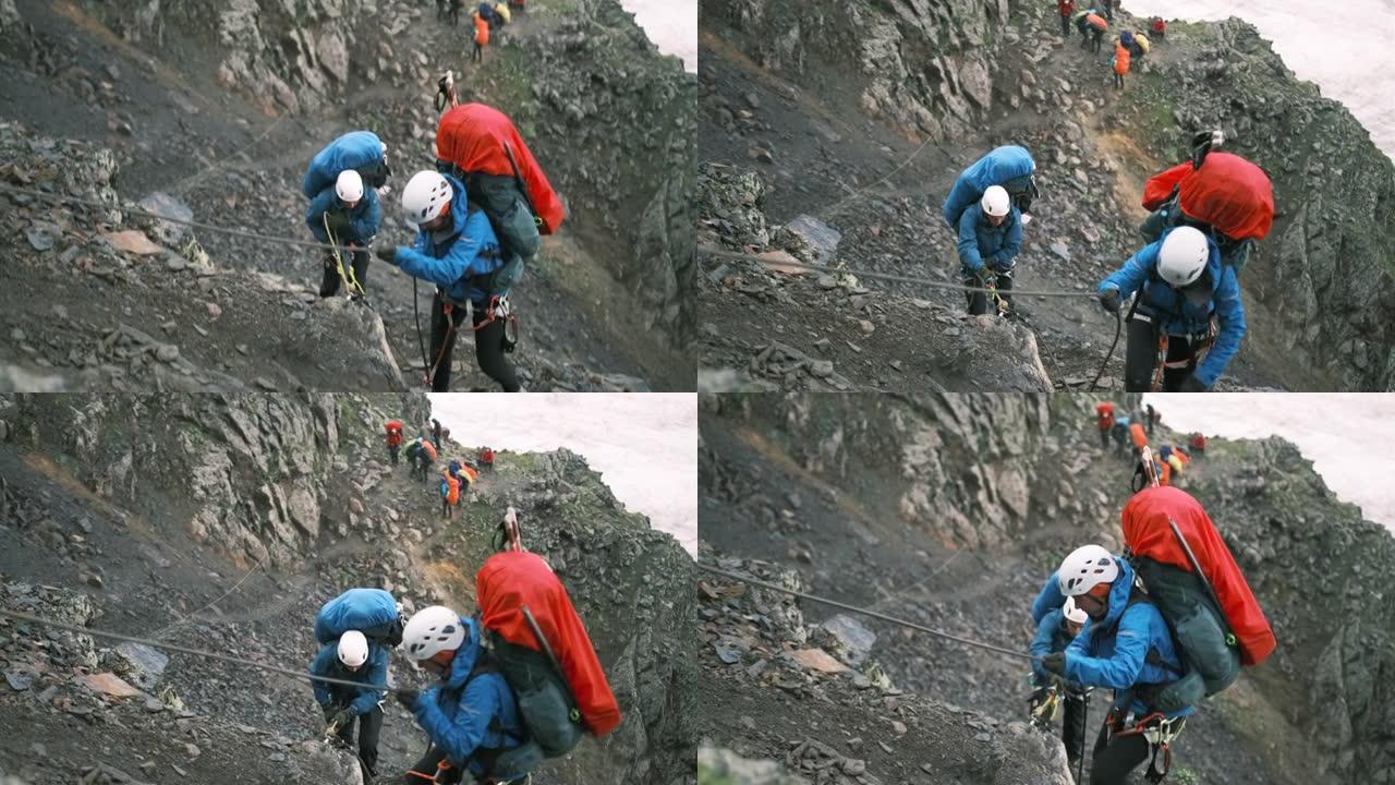 几个登山者抓住钢绳爬上山