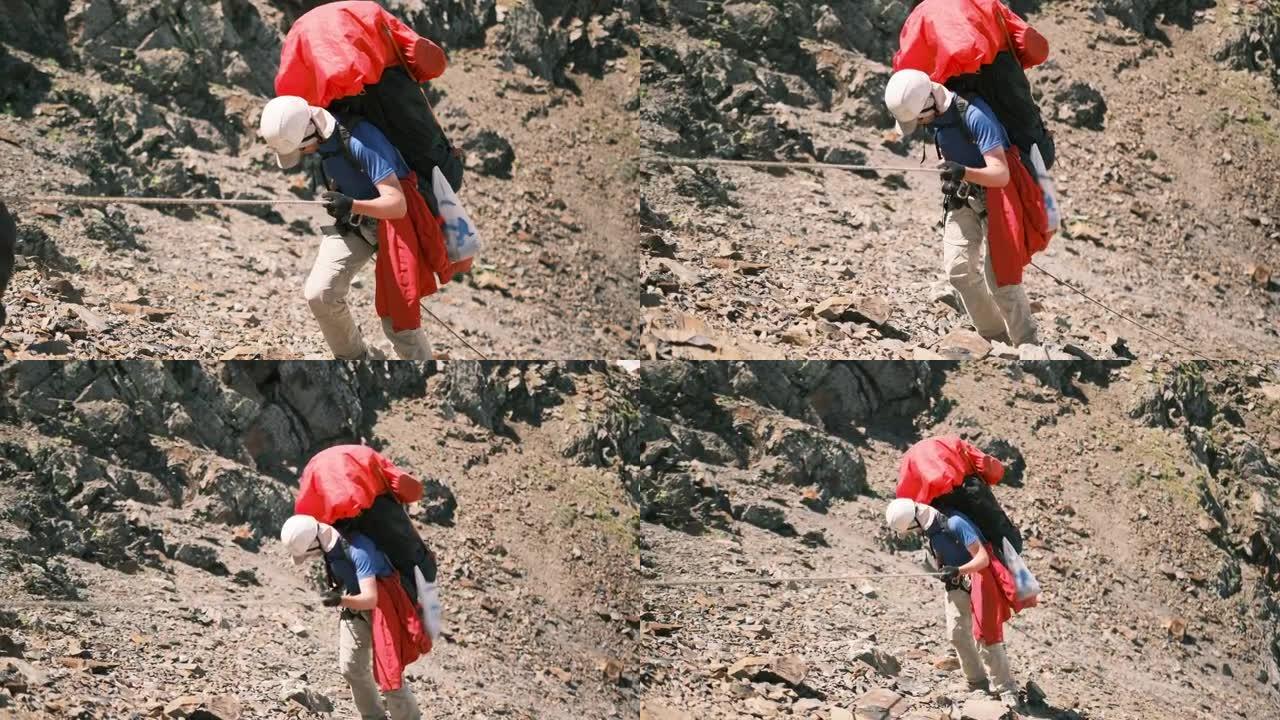 一个背着背包的登山者用带保护系统的绳子下山。