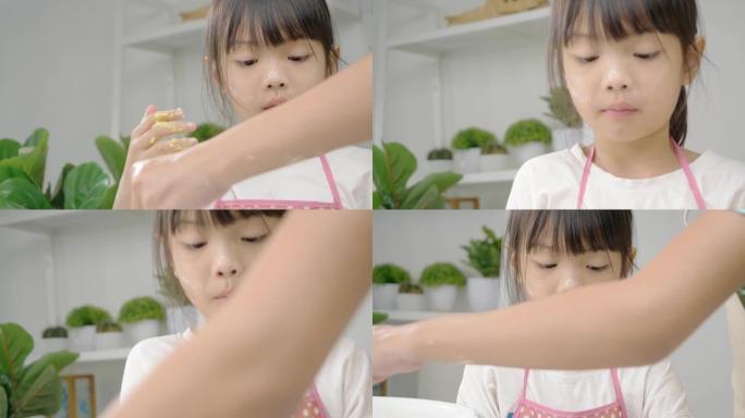 快乐的亚洲儿童在家里一起学习制作饼干，女孩在手里打谷面团。
